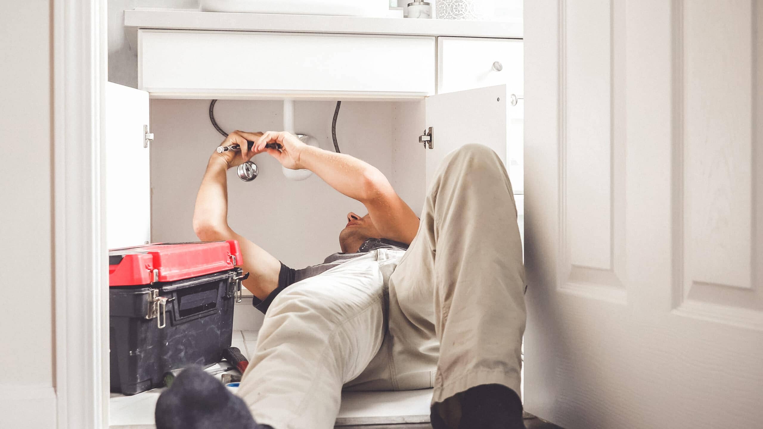 Technician fixing a water leak in a home plumbing system
