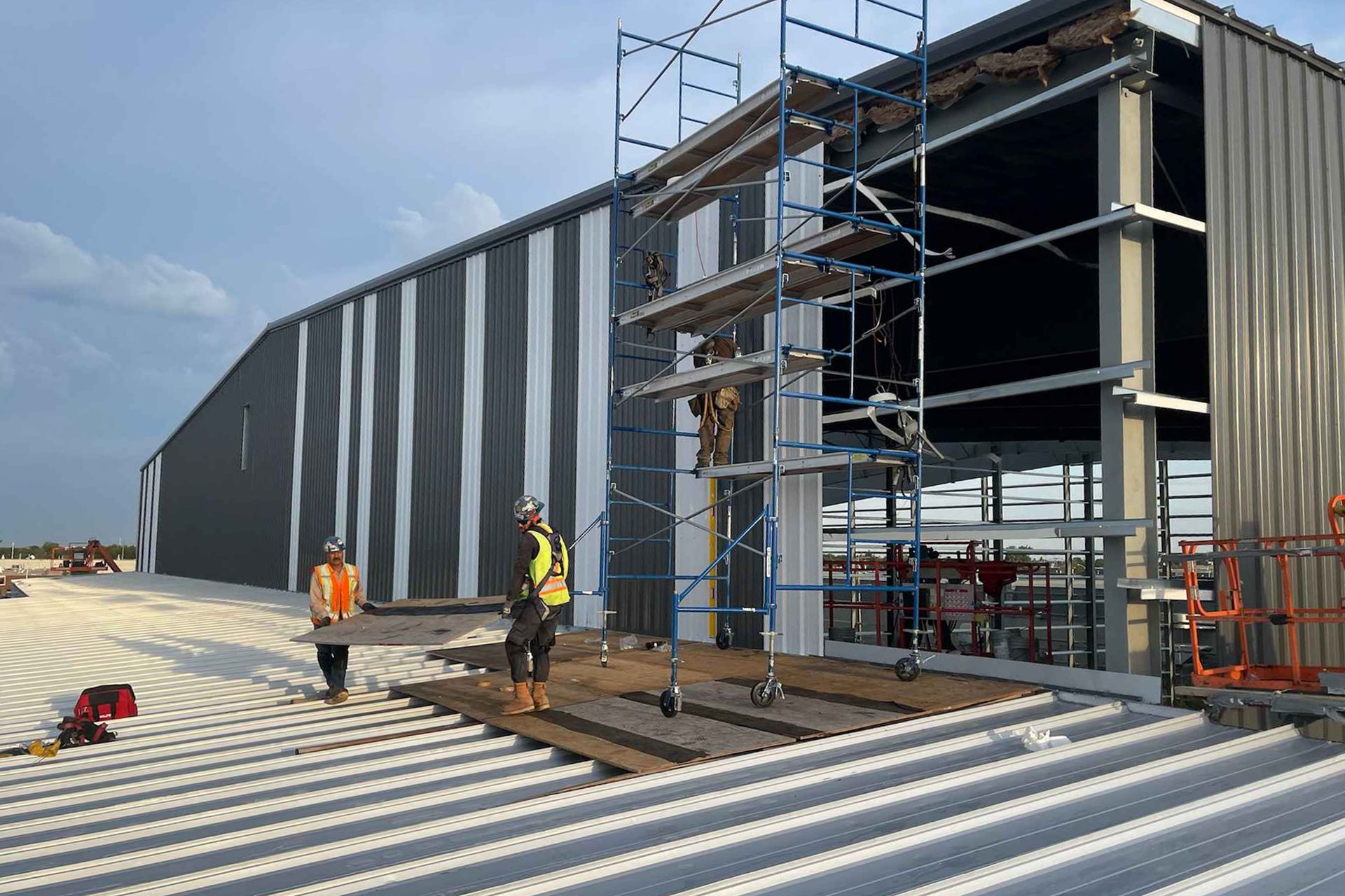 Tradespeople add metal panels to an industrial building in Winnipeg